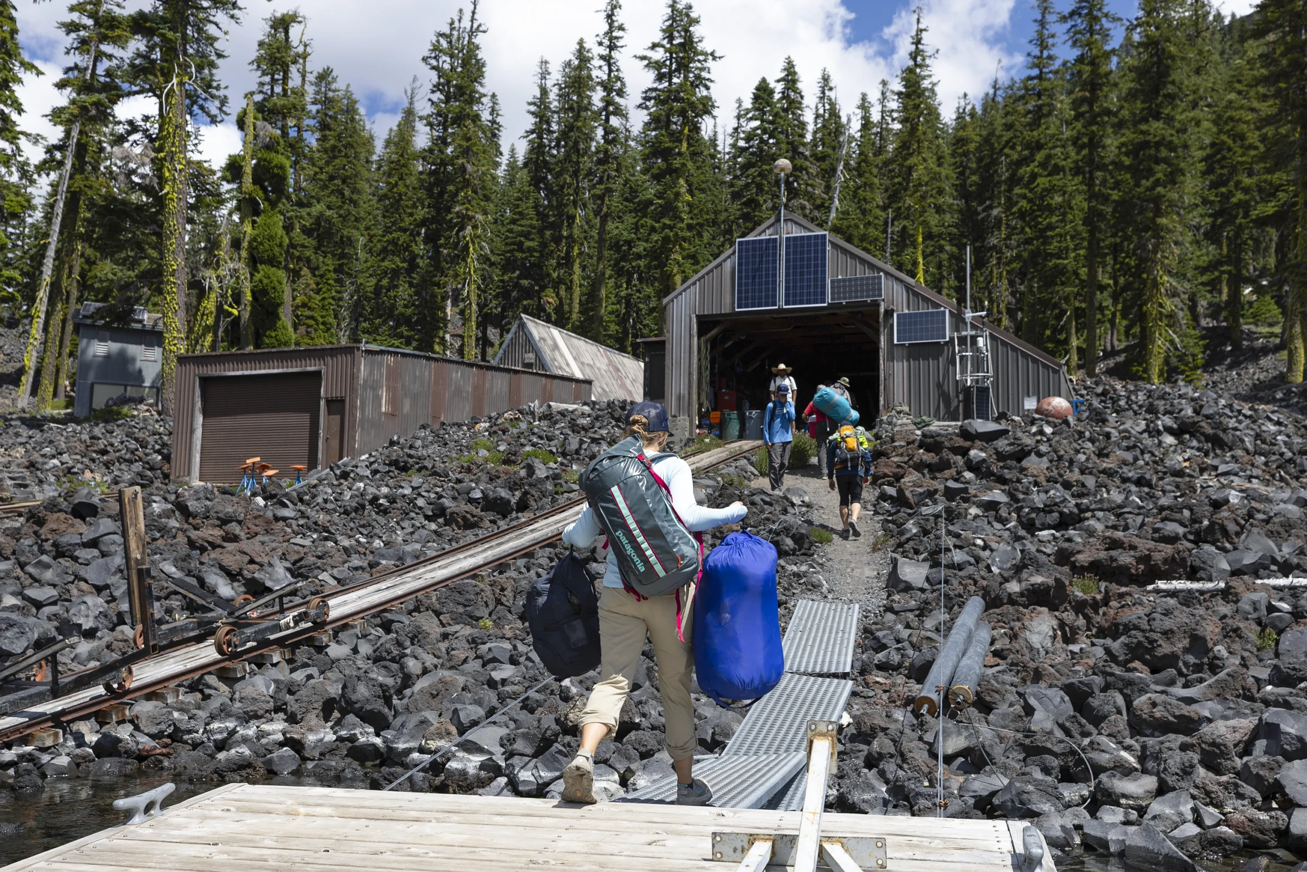 They carry their belongings through volcanic gravel to the rustic station.