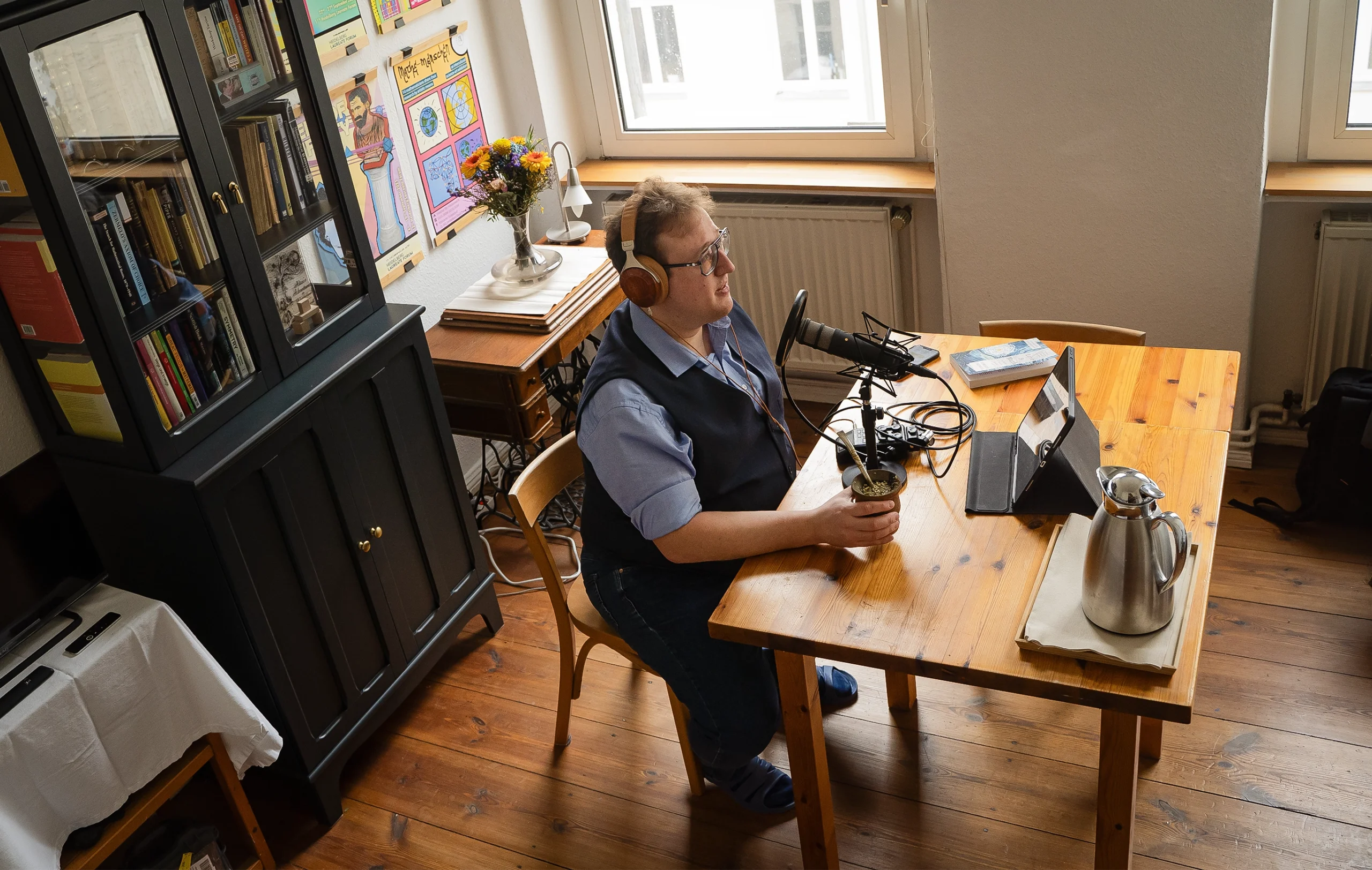 Man recording a podcast at a wooden desk.