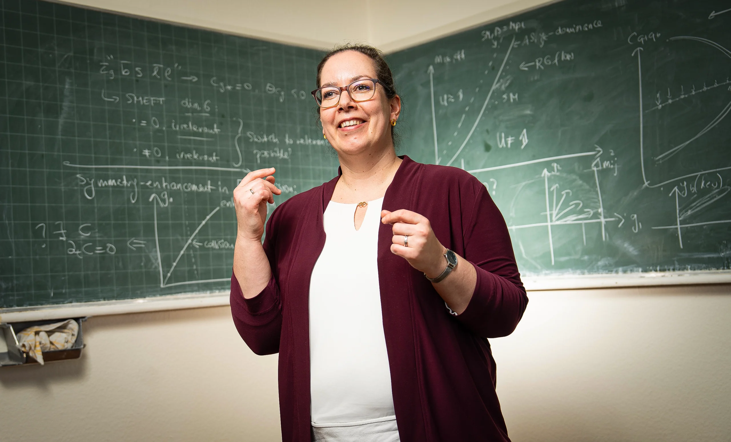 A woman gestures at a blackboard while speaking with a collaborator.