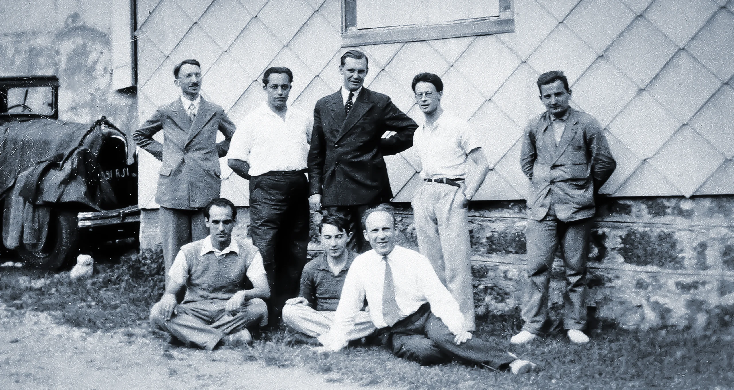 Black-and-white photo of a group of men posing in front of a building.