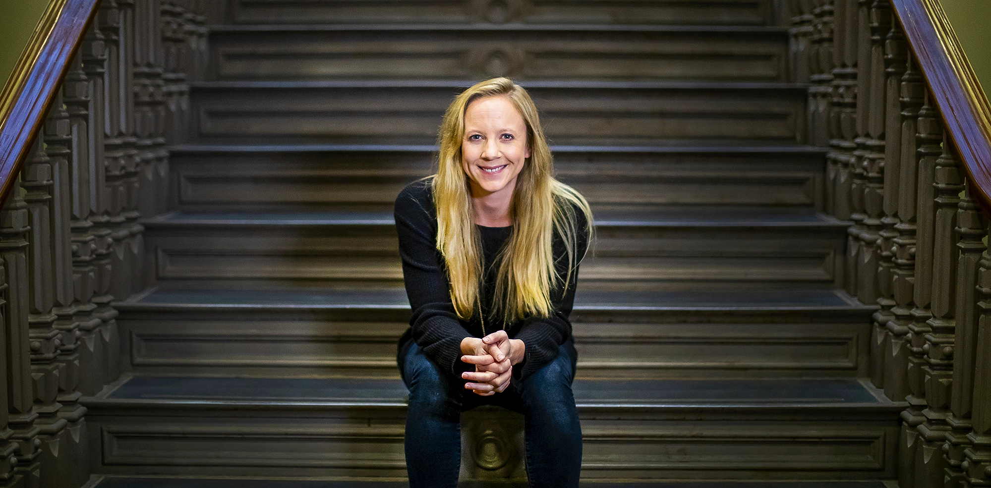 Blond woman sitting on a staircase.