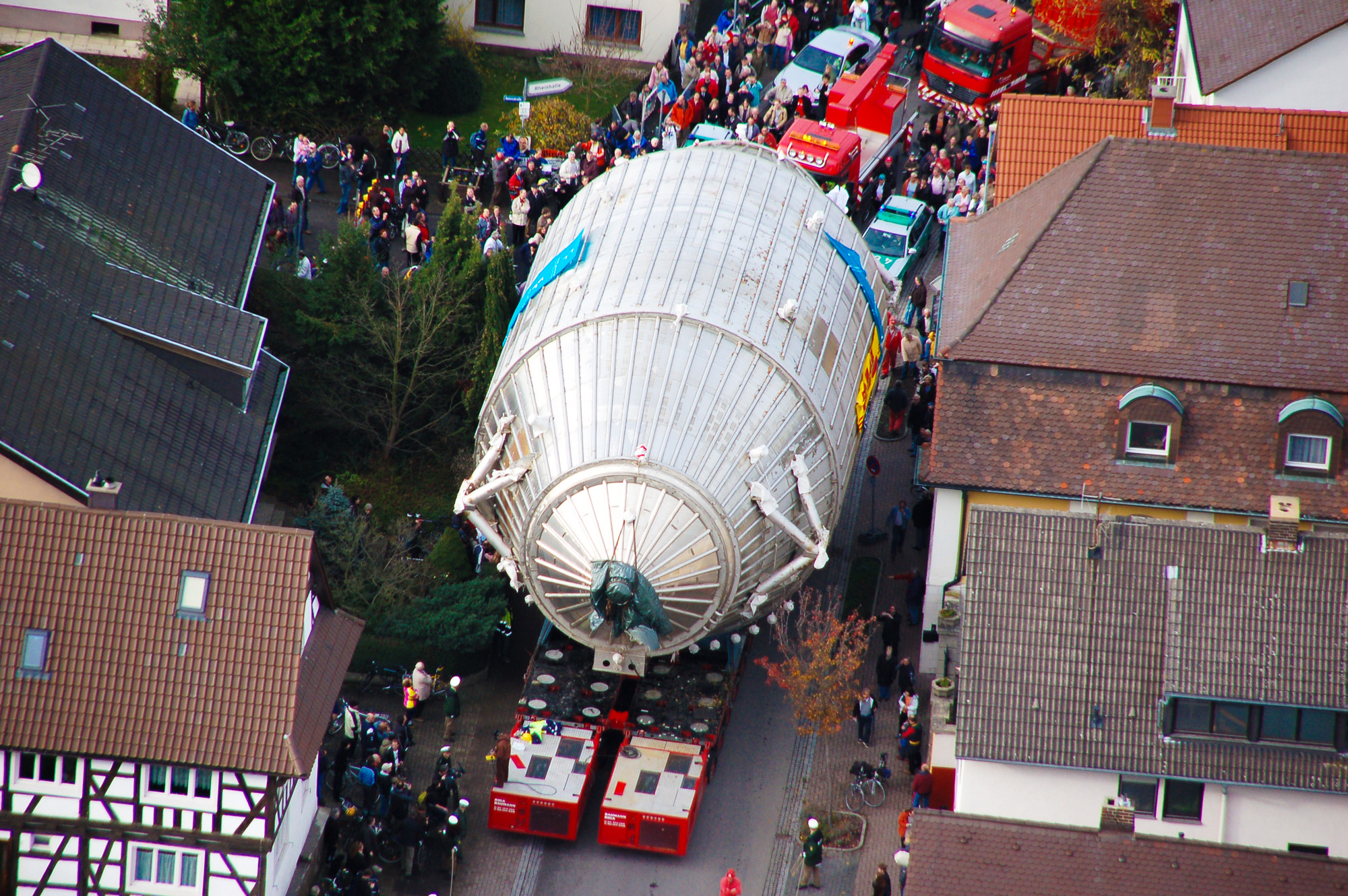 An enormous steel canister on a flatbed truck in a historic European town.