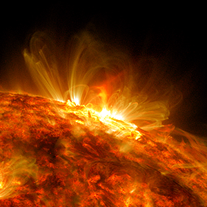 Video showing a slow-moving edge of the red-colored sun pointing upwards. A large solar flare erupts, starting at the right and moving towards the center as the edge of the sun rotates anti-clockwise.
