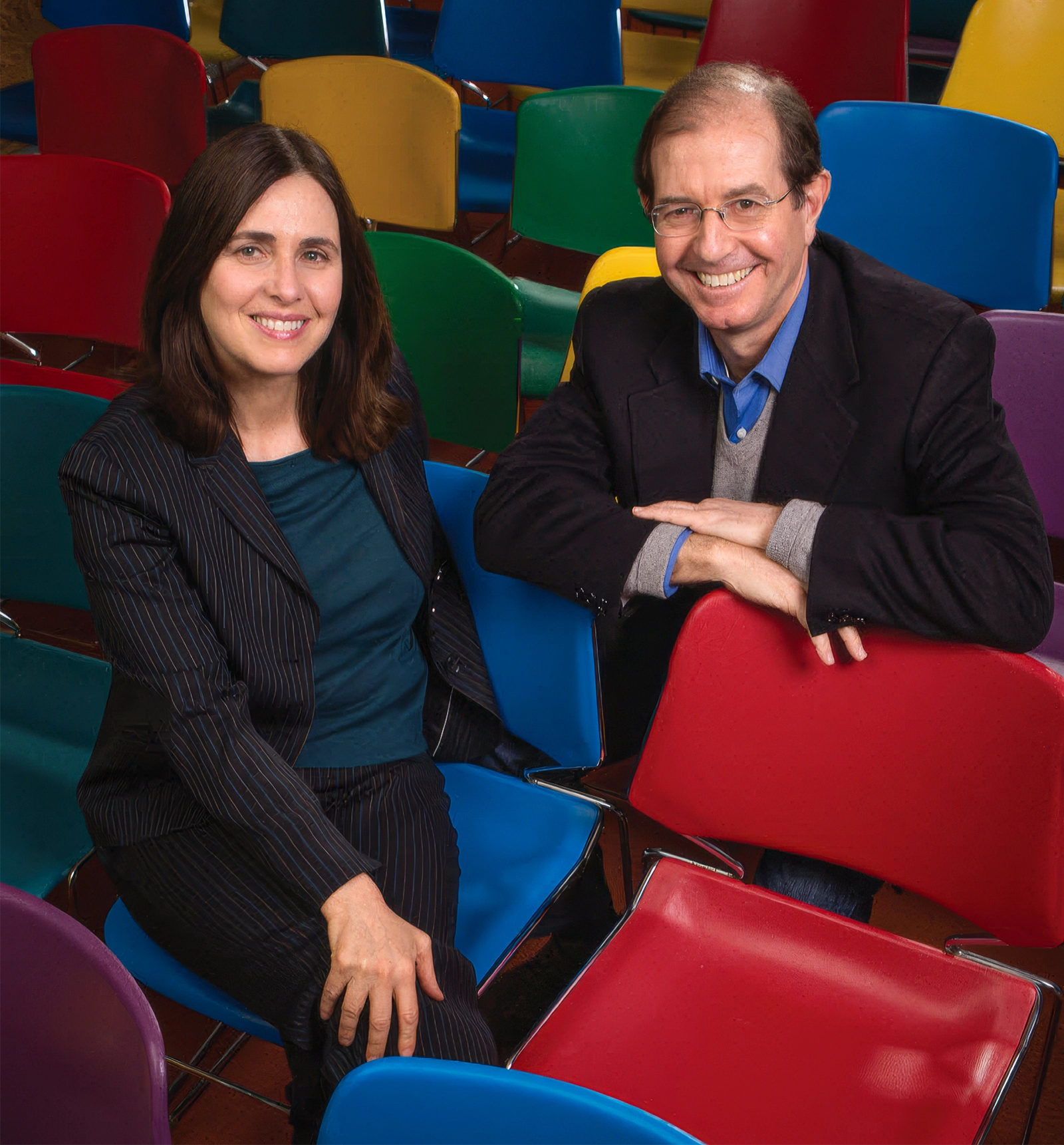 Man and woman sitting in colorful chairs.