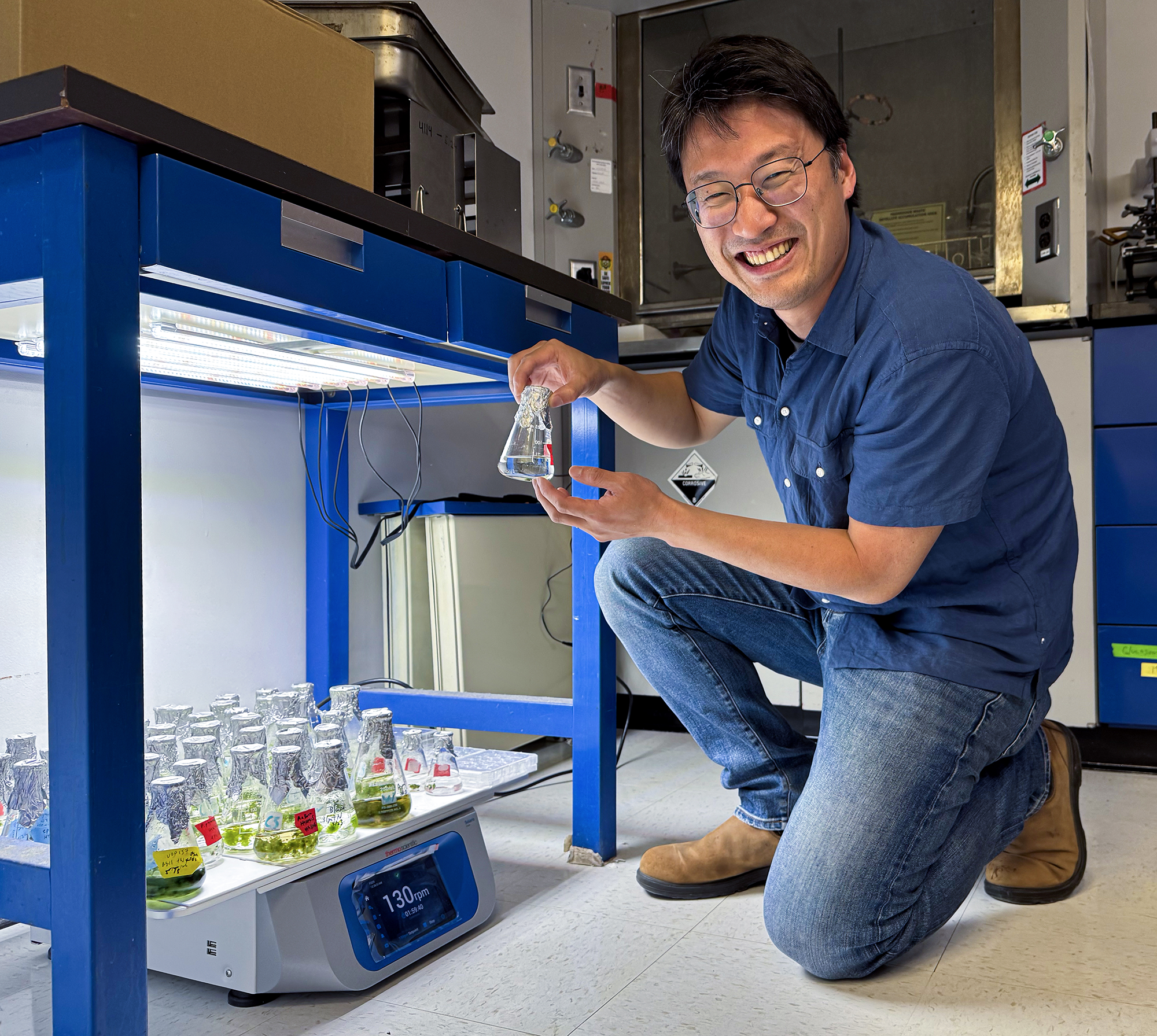Fai-Wei Li holds a flask of cyanobacteria.