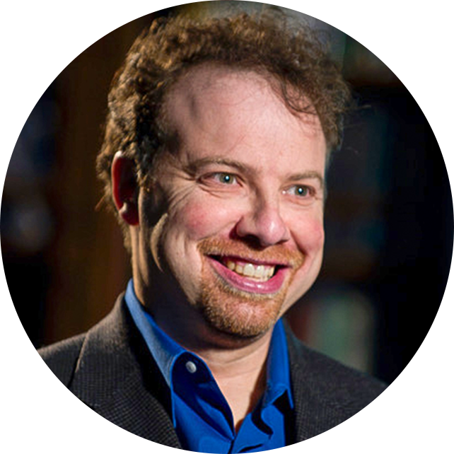 A smiling man in a jacket and blue button down
