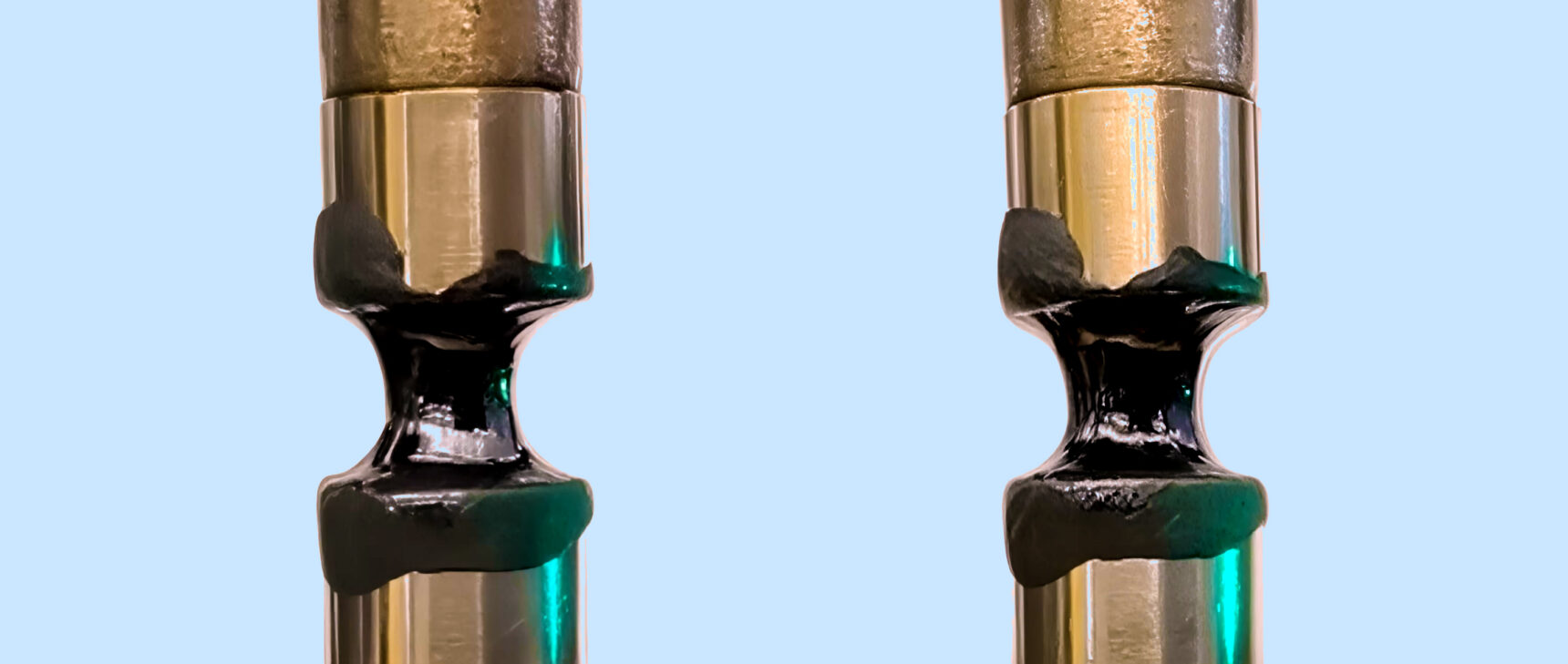 Video showing black, gooey liquids pulled apart in an extensional rheometer. In the first video, the liquid stretches. In the second video, the liquid cracks apart.