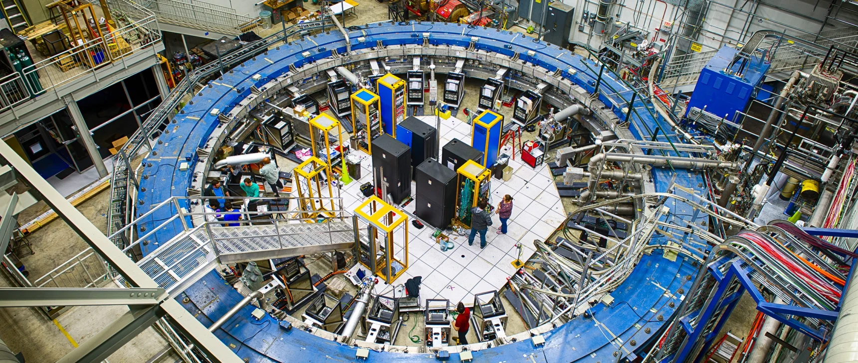 A blue magnetic ring nearly fills a warehouse-sized laboratory.