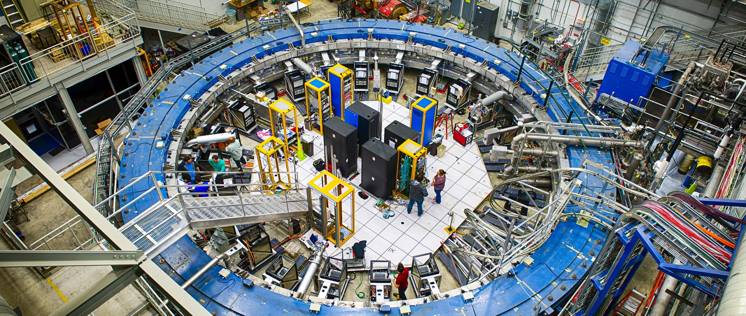 A blue magnetic ring nearly fills a warehouse-sized laboratory.