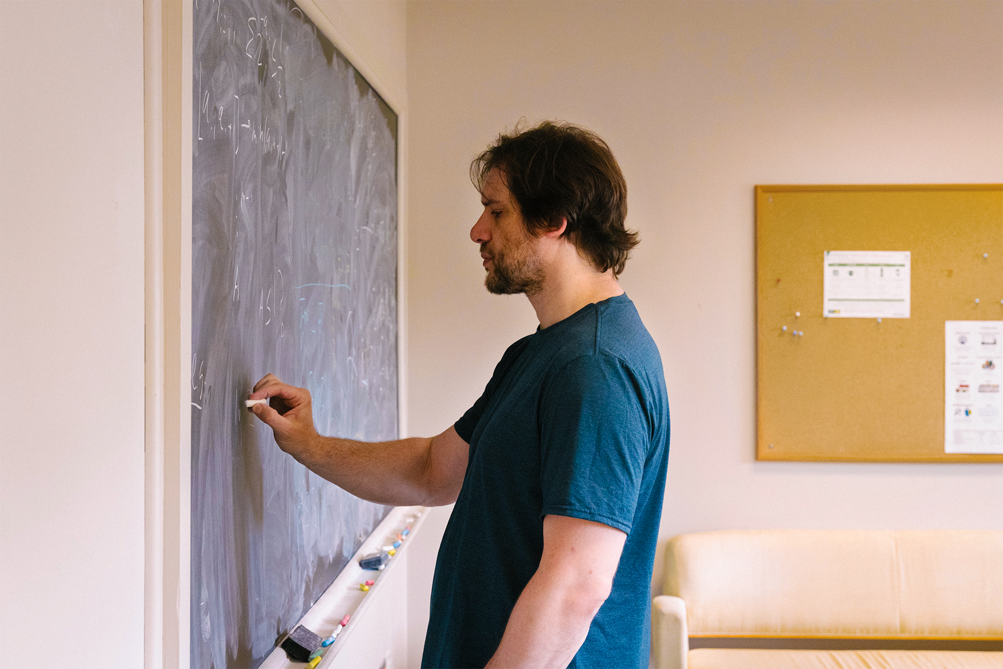 A man writing on a chalk board.