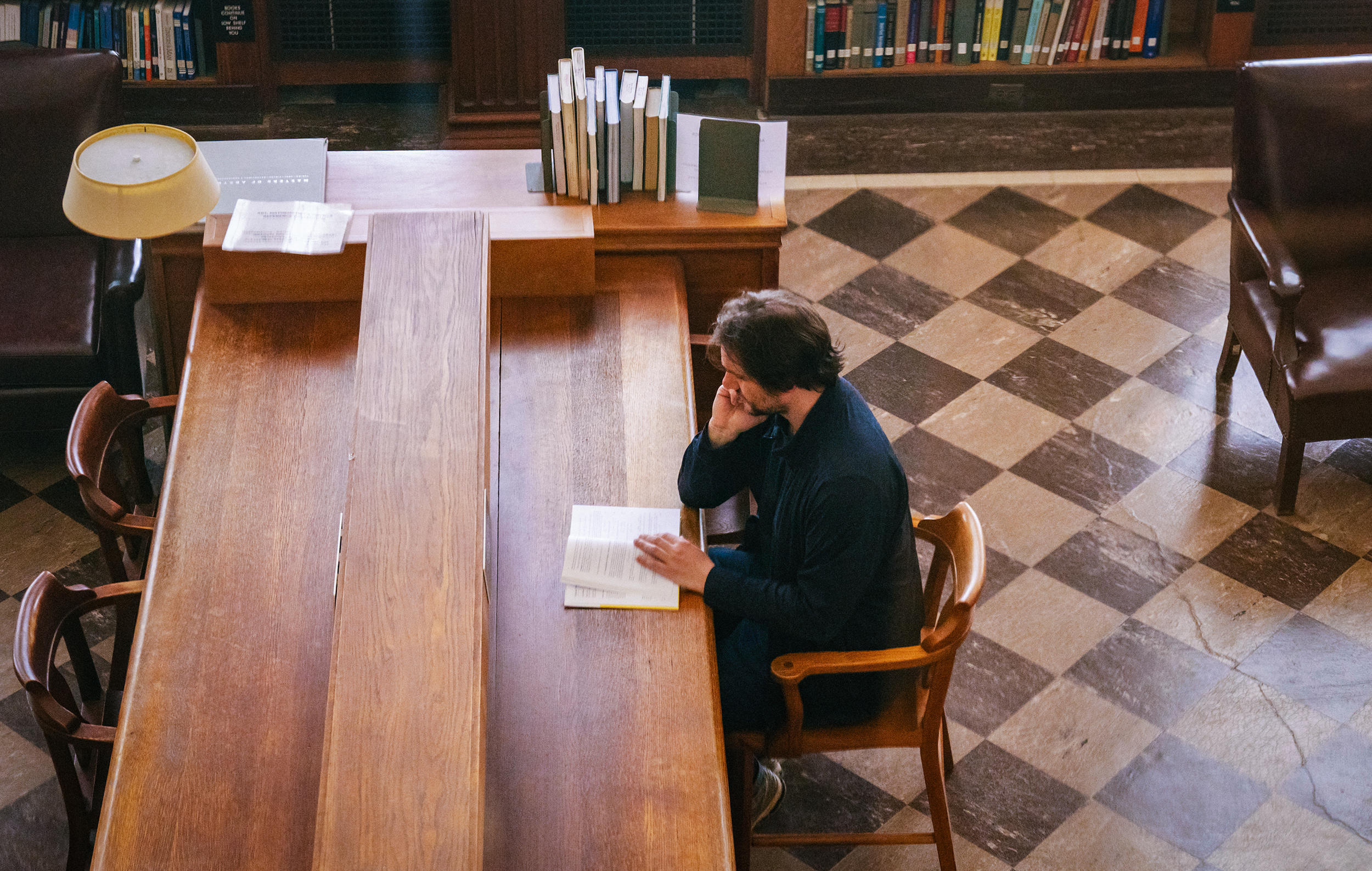 A man reading at a desk in a library.