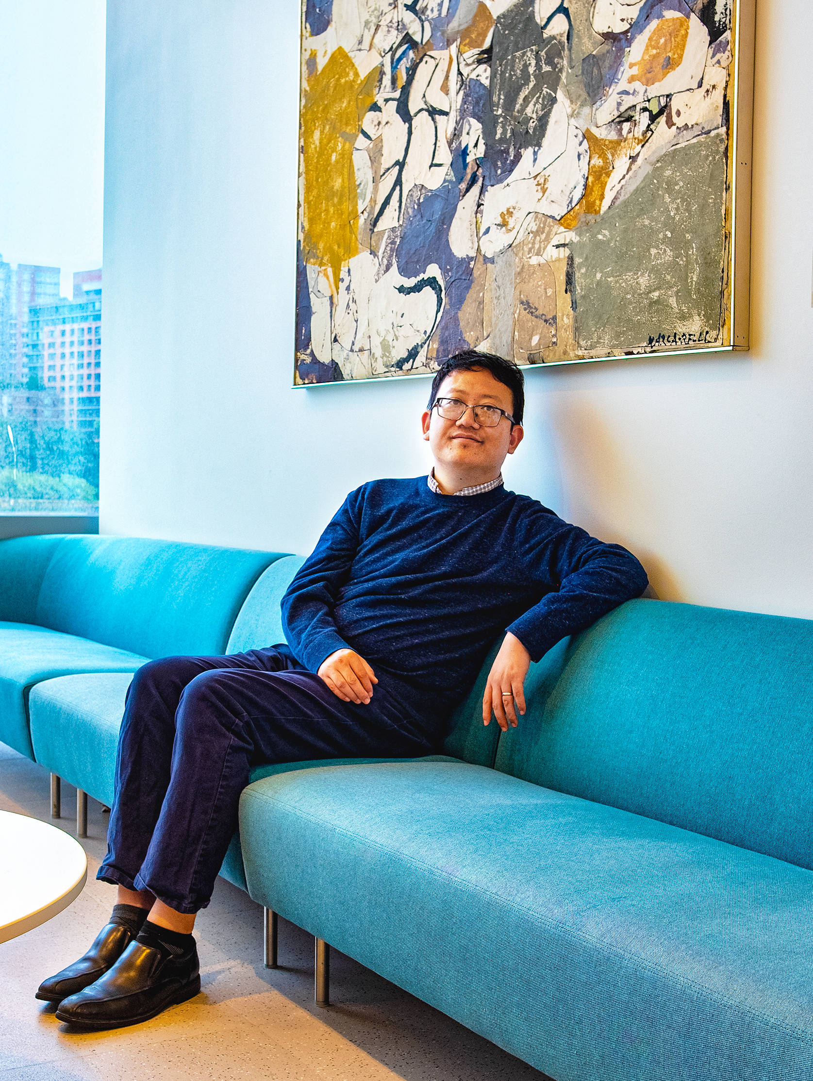 A man in a sweater sitting on a blue couch