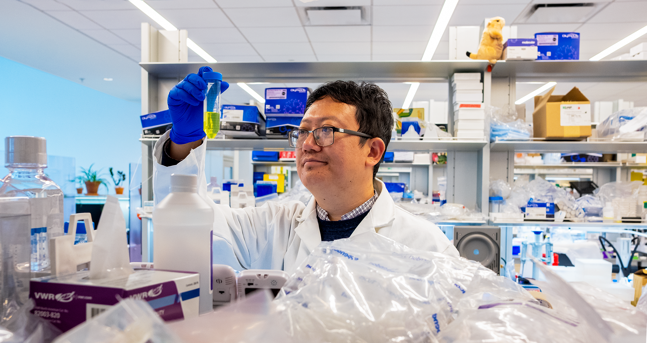 A man in a lab coat peering at a test tube
