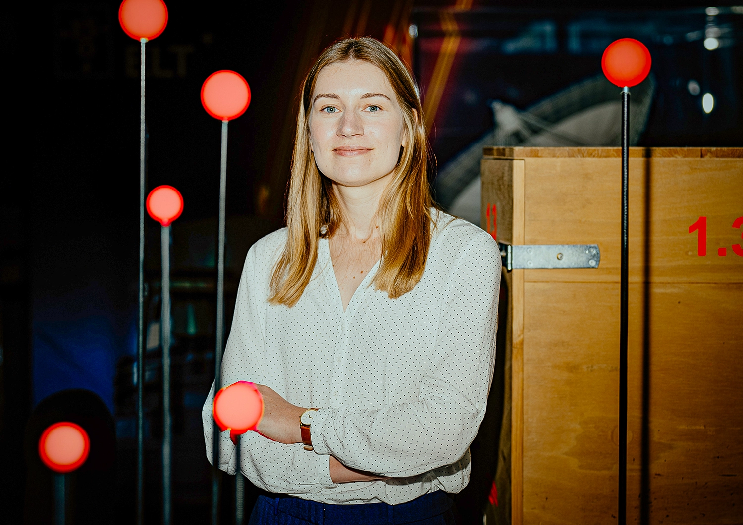 A woman stands in the midst of small red circles mounted on poles.