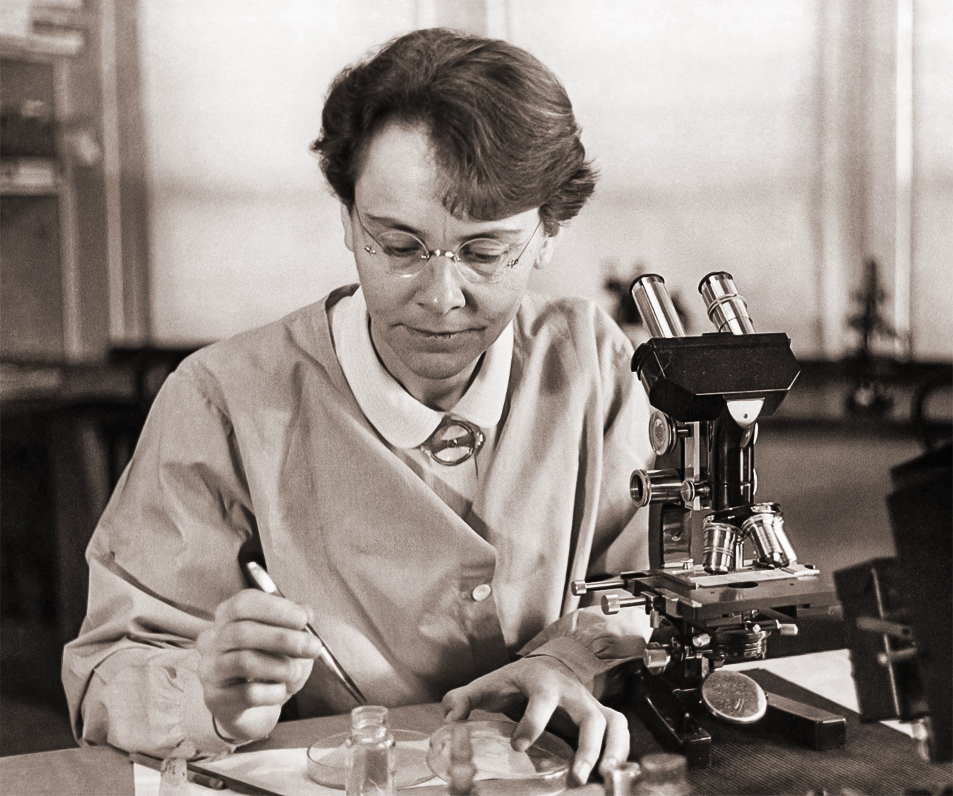 Barbara McClintock sits at a microscope.