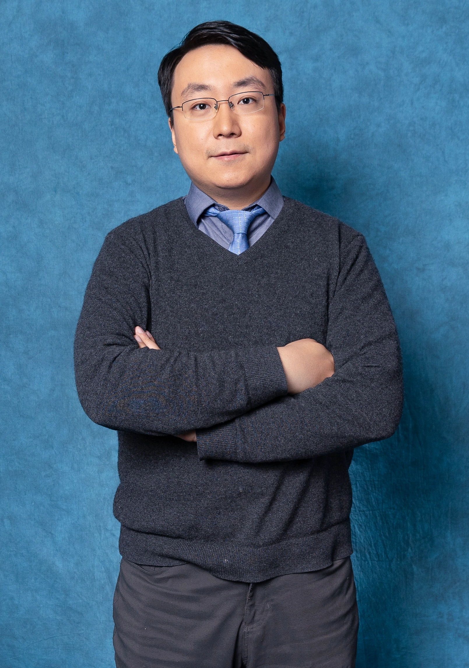 Portrait of a man in a sweater and tie.