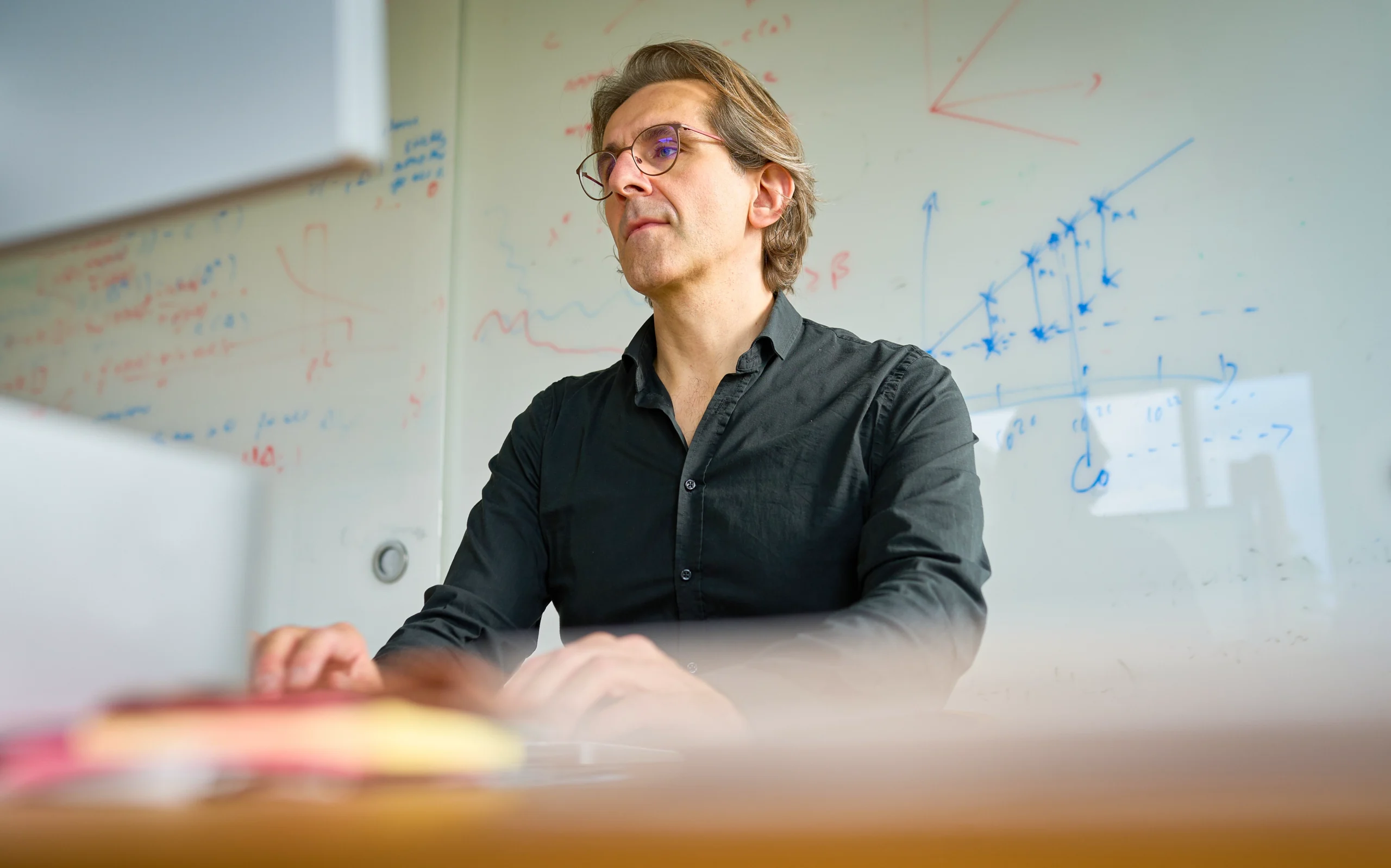 Man sitting at his desk in front of a whiteboard.