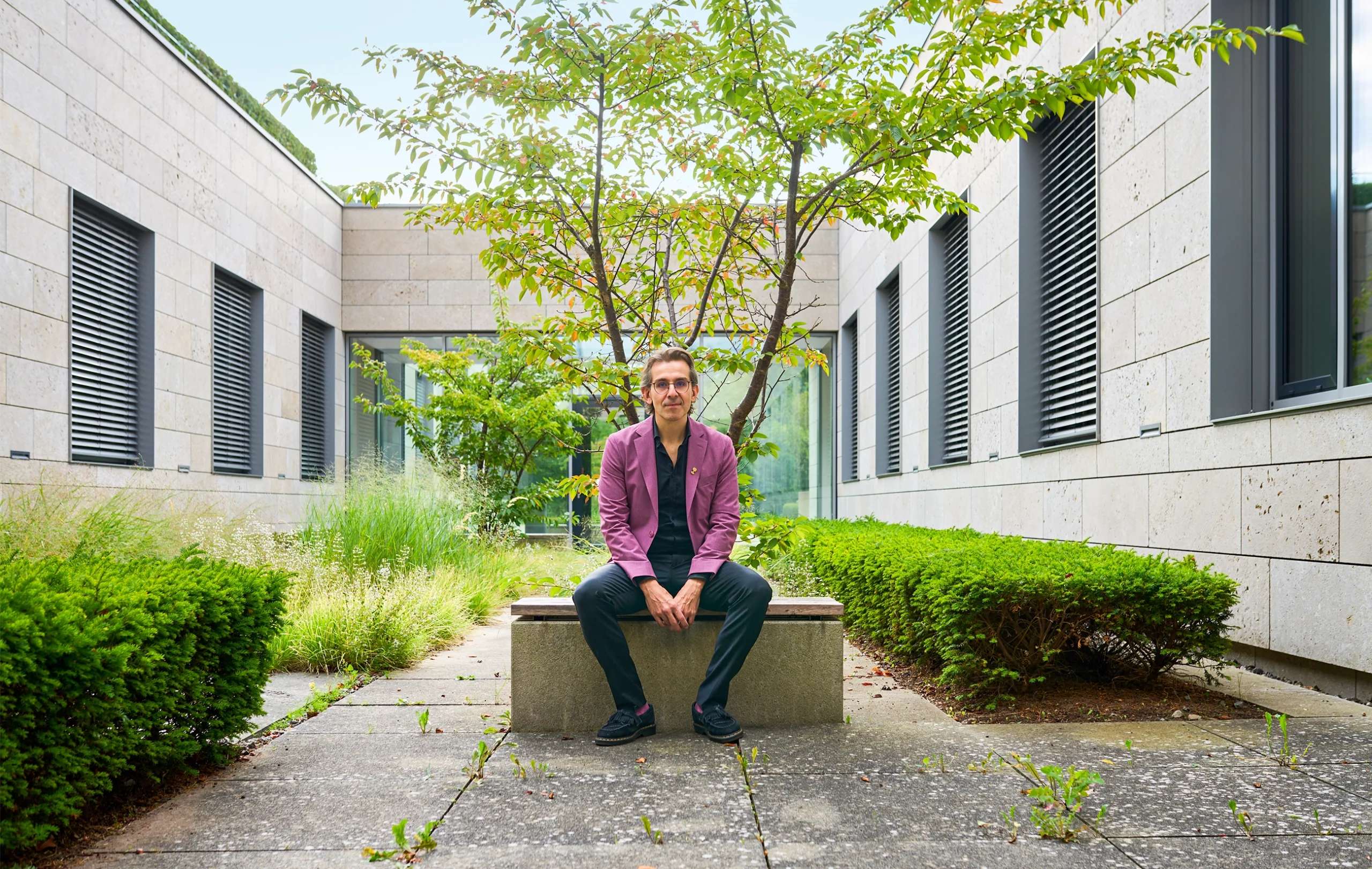 Man in a purple jacket sitting outdoors.