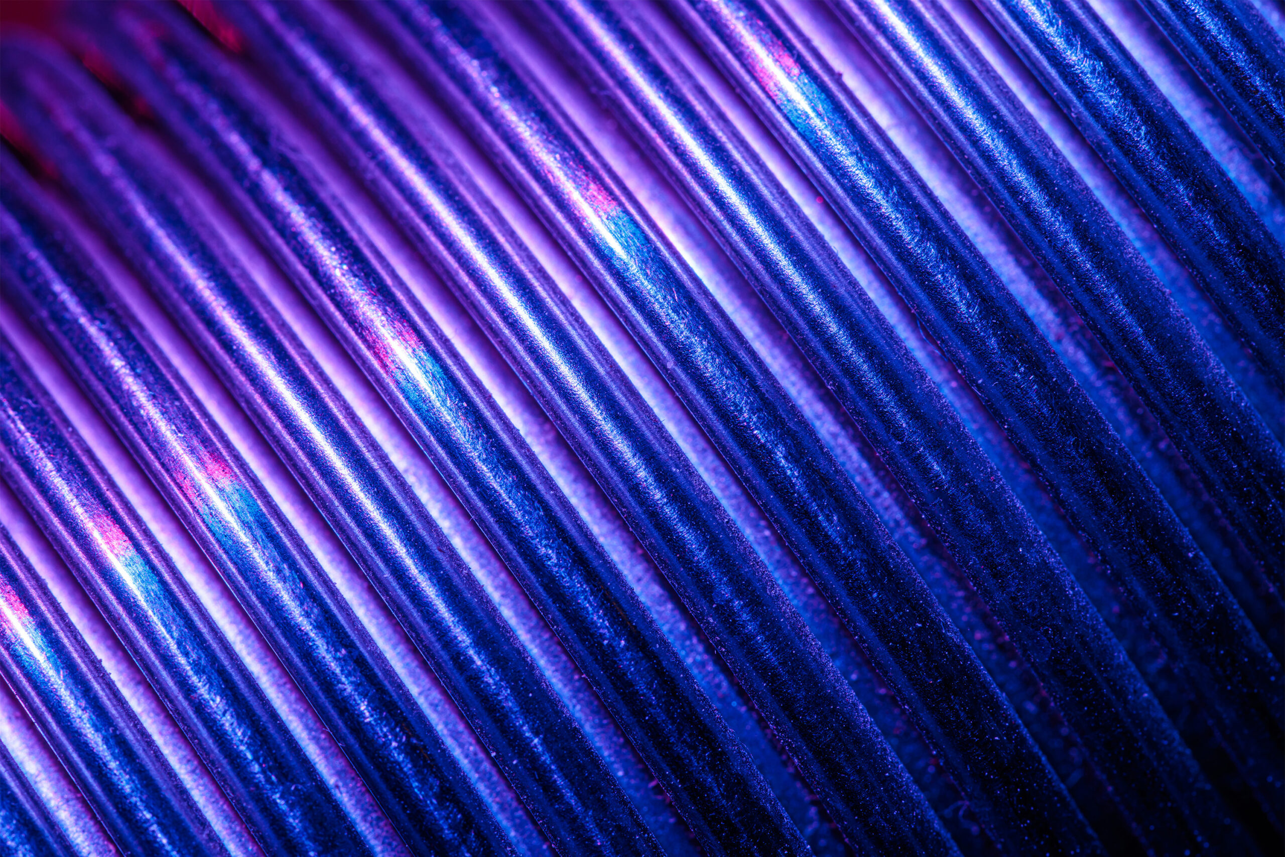 Close-up of tightly packed parallel ridges running diagonally across the frame, lit in deep blue and purple tones.