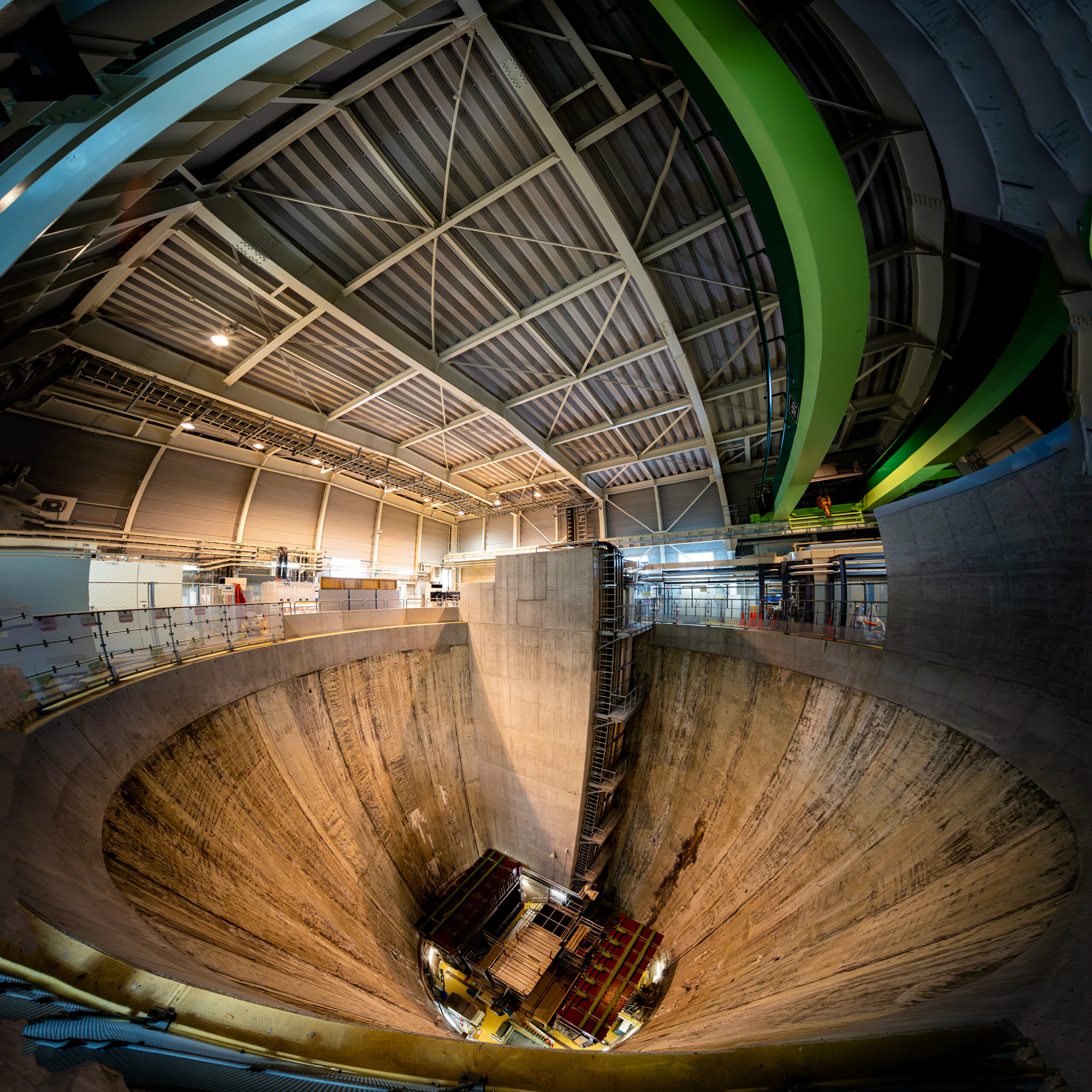 A high-ceilinged industrial hall with a metal roof and fluorescent lighting