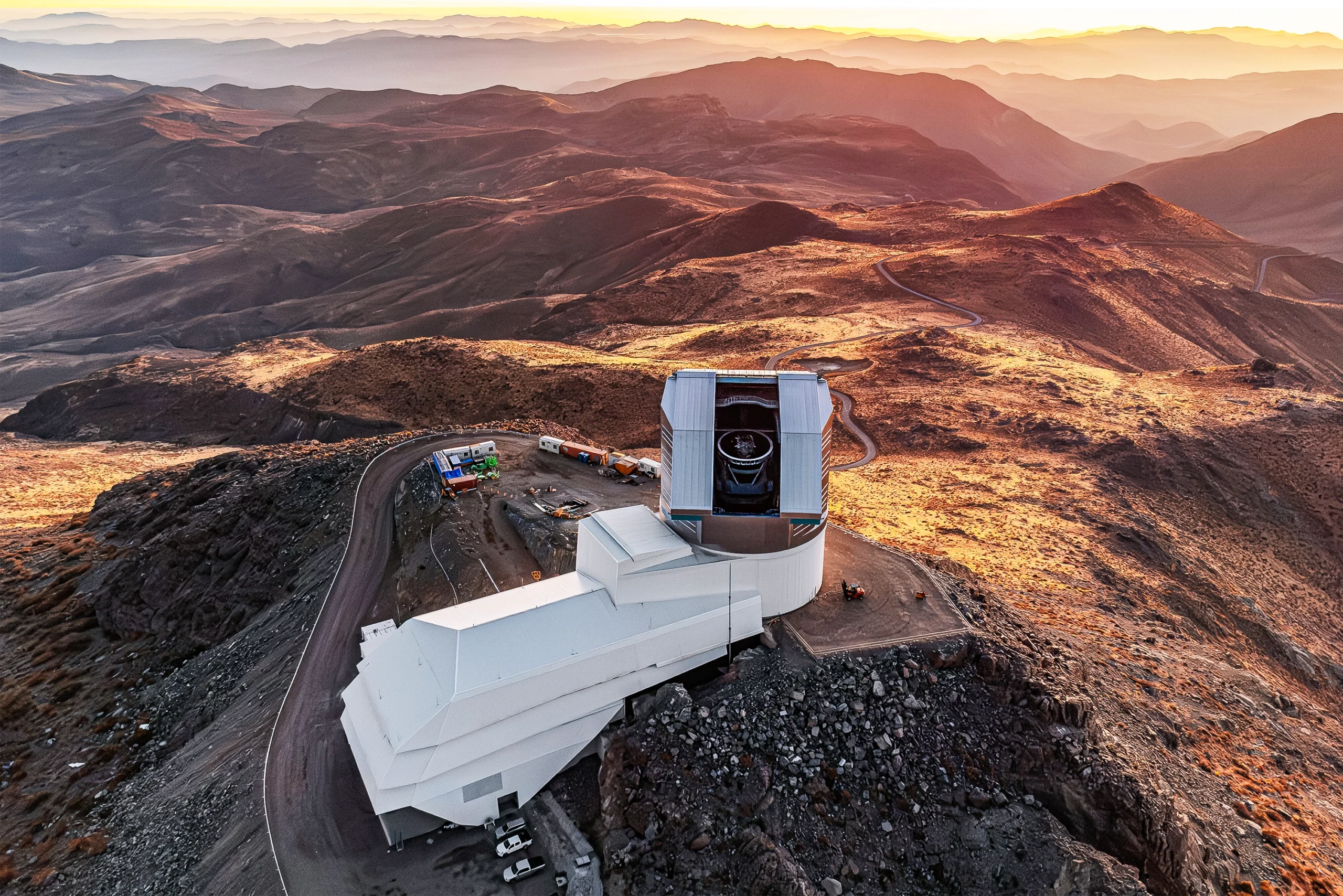 A bird’s-eye view of the Rubin Observatory in a tawny mountainous landscape.