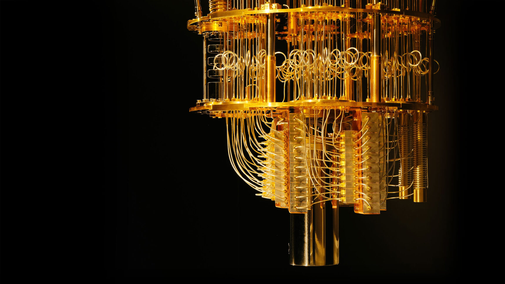Close-up view of a chandelier-like dilution refrigerator used in quantum computing, with many gold-colored wires hanging between levels of gold plates.