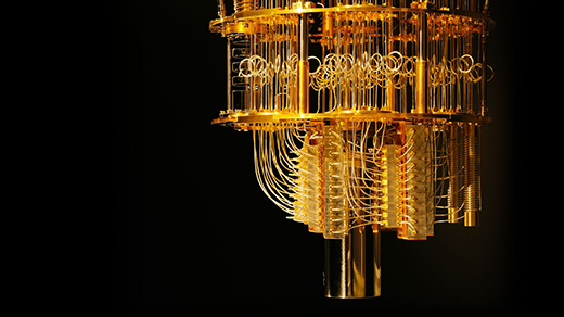 Close-up view of a chandelier-like dilution refrigerator used in quantum computing, with many gold-colored wires hanging between levels of gold plates.