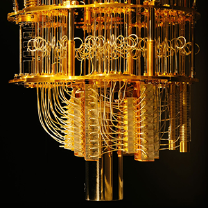 Close-up view of a chandelier-like dilution refrigerator used in quantum computing, with many gold-colored wires hanging between levels of gold plates.